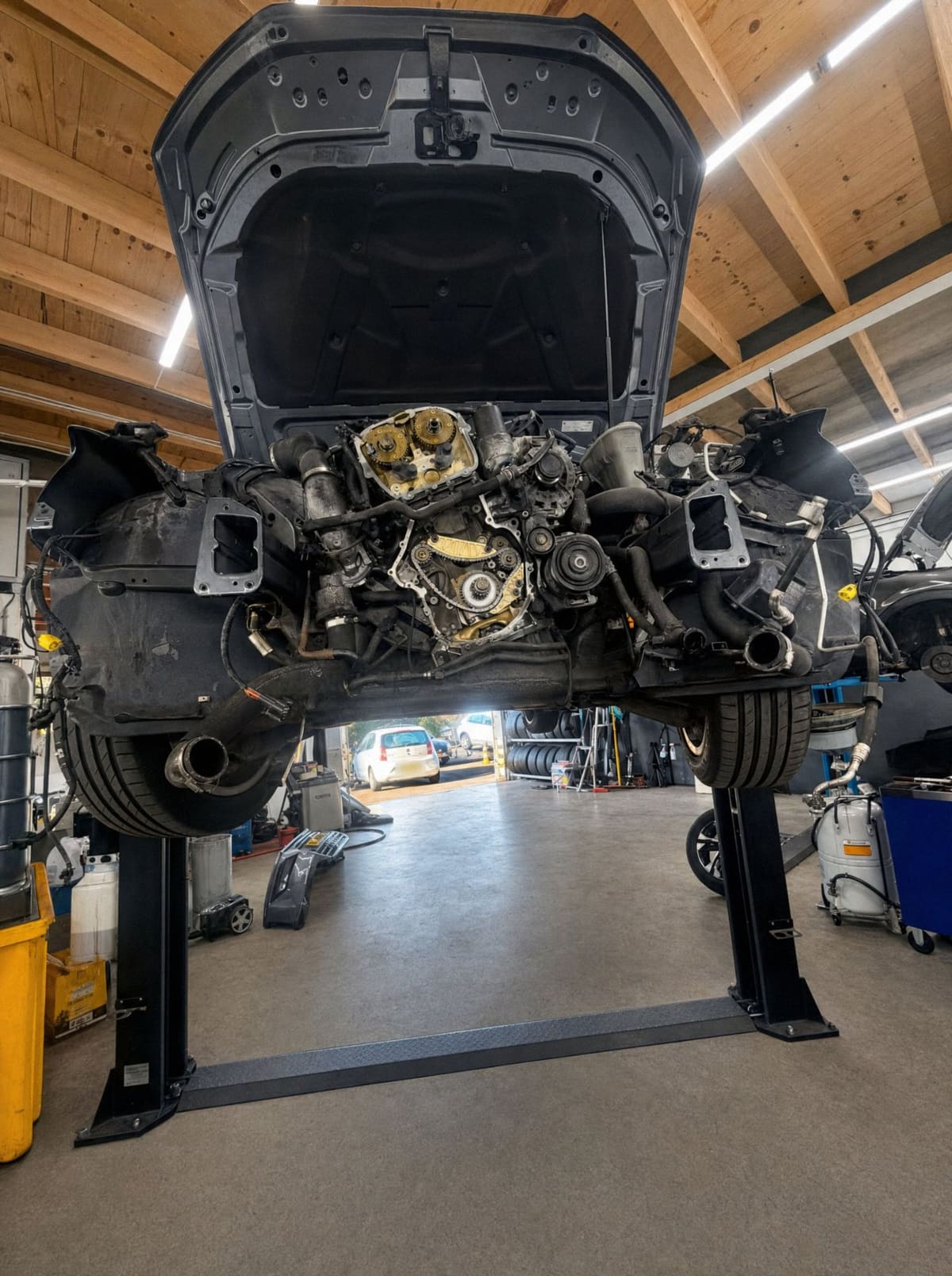 Auto op de brug met de voorkant van de motor open in de werkplaats van MT Autoservice in Almere